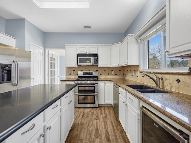 kitchen with sink, light hardwood / wood-style flooring, stainless steel appliances, and white cabinets