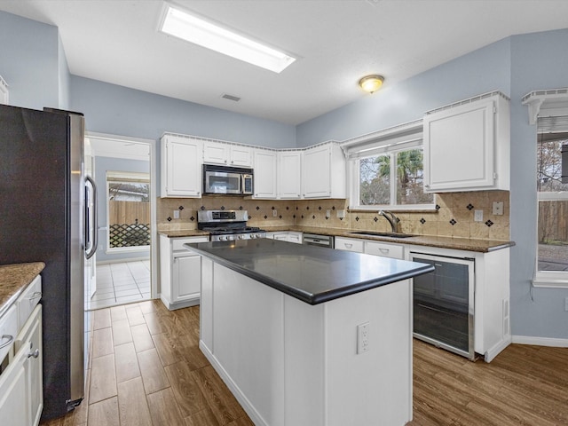 kitchen with stainless steel appliances, a center island, sink, and white cabinets