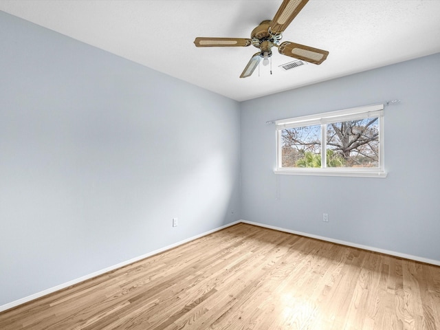 empty room featuring baseboards, visible vents, ceiling fan, and wood finished floors