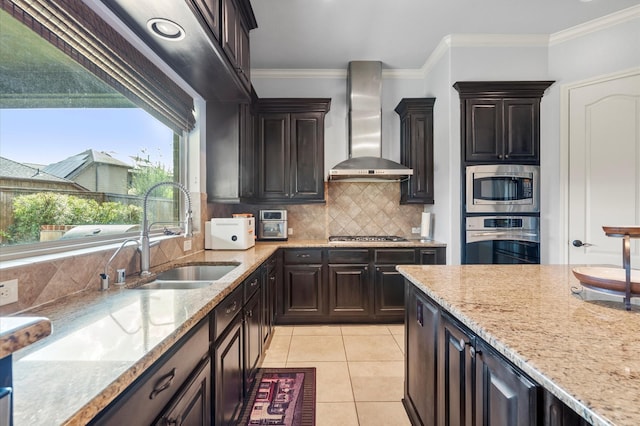 kitchen featuring sink, backsplash, stainless steel appliances, crown molding, and wall chimney range hood