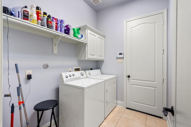 laundry room with cabinets, light tile patterned floors, and washing machine and clothes dryer