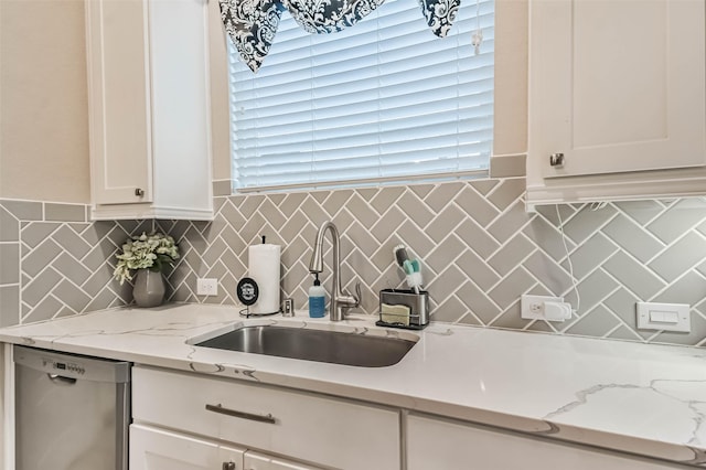 kitchen featuring white cabinetry, stainless steel dishwasher, sink, and light stone counters