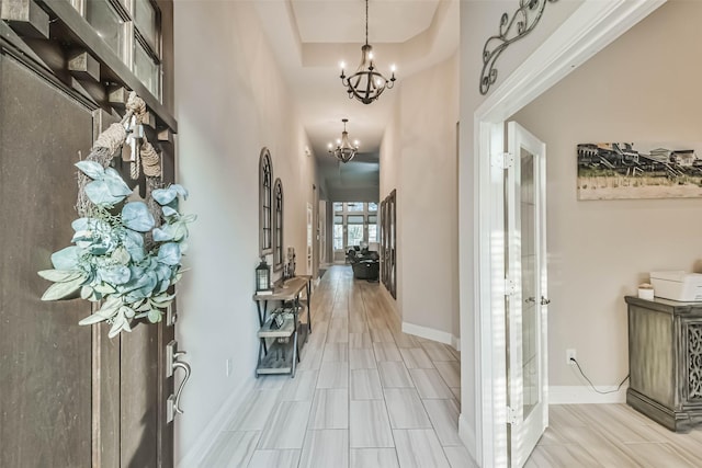 hallway with a towering ceiling and a notable chandelier