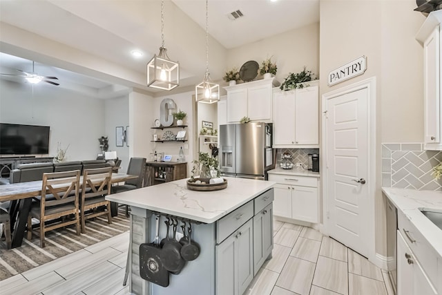 kitchen featuring a breakfast bar, pendant lighting, white cabinetry, a center island, and stainless steel refrigerator with ice dispenser