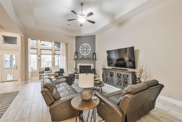 living room with a raised ceiling and ceiling fan