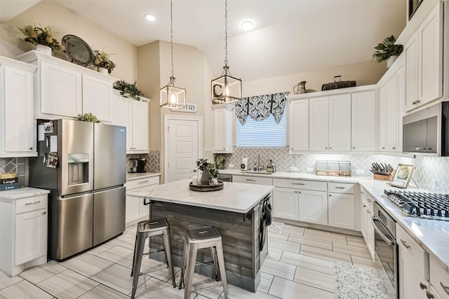 kitchen with white cabinetry, appliances with stainless steel finishes, a kitchen bar, and a kitchen island