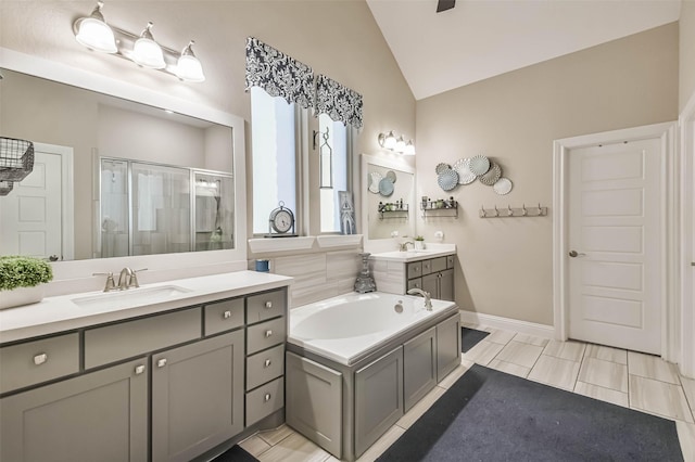 bathroom with independent shower and bath, vaulted ceiling, and vanity