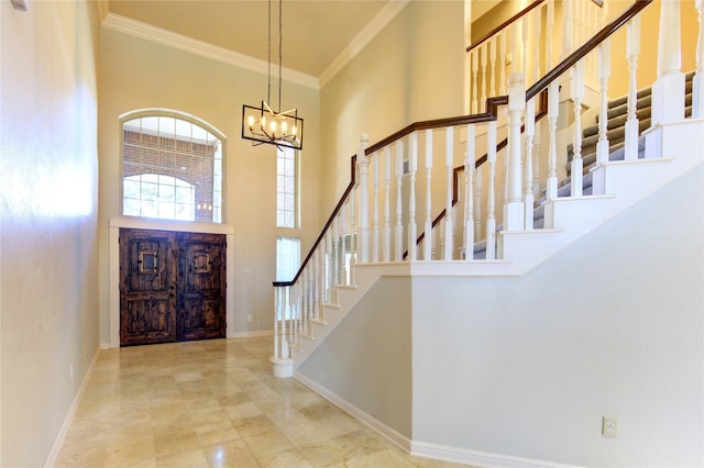 foyer with a towering ceiling, ornamental molding, and a chandelier