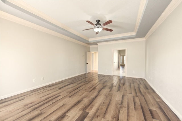 empty room featuring crown molding, ceiling fan, a raised ceiling, and hardwood / wood-style floors