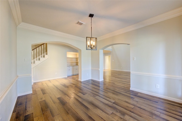 empty room featuring crown molding, dark wood-type flooring, and an inviting chandelier