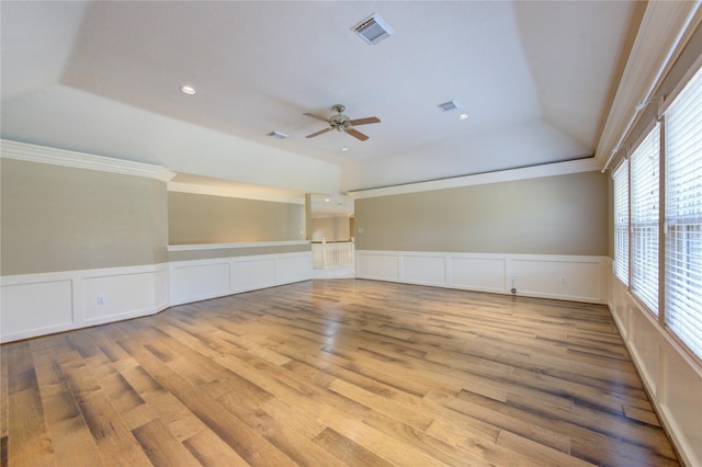 unfurnished room featuring crown molding, a tray ceiling, and light wood-type flooring