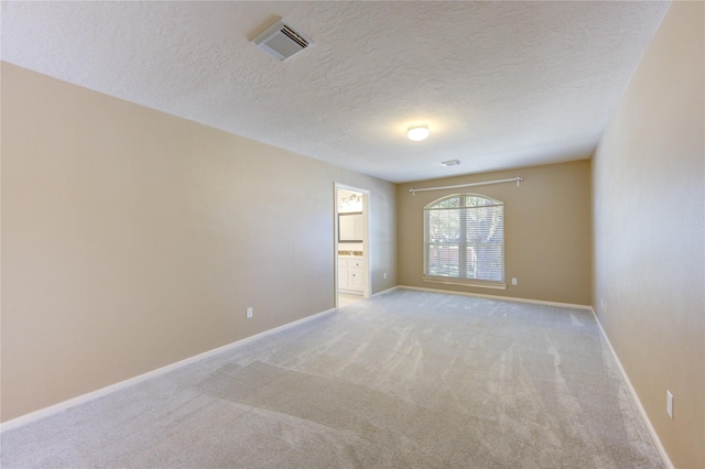 unfurnished room with light colored carpet and a textured ceiling