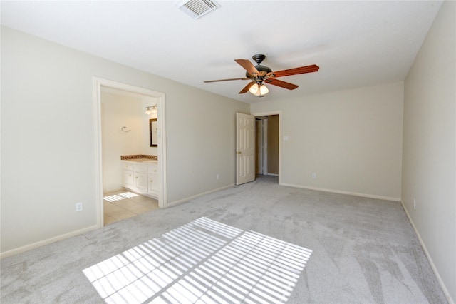 unfurnished bedroom featuring ceiling fan, light colored carpet, and ensuite bath