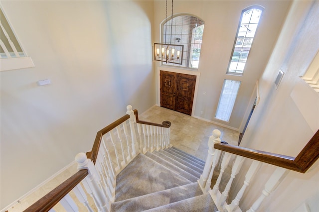 staircase featuring a high ceiling and a chandelier