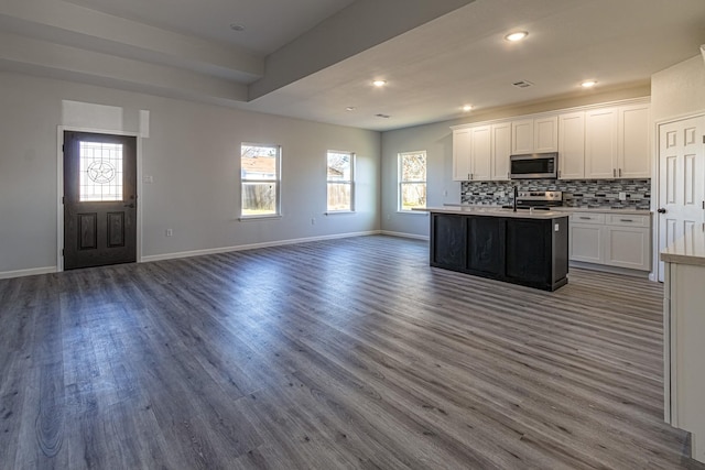 kitchen featuring white cabinetry, appliances with stainless steel finishes, a kitchen island with sink, and backsplash