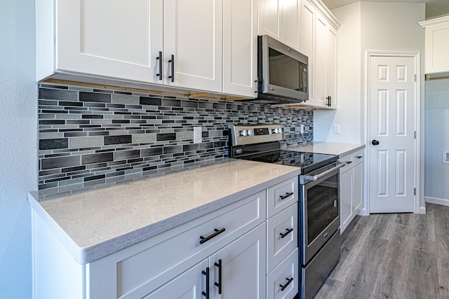 kitchen featuring light hardwood / wood-style flooring, appliances with stainless steel finishes, light stone countertops, decorative backsplash, and white cabinets