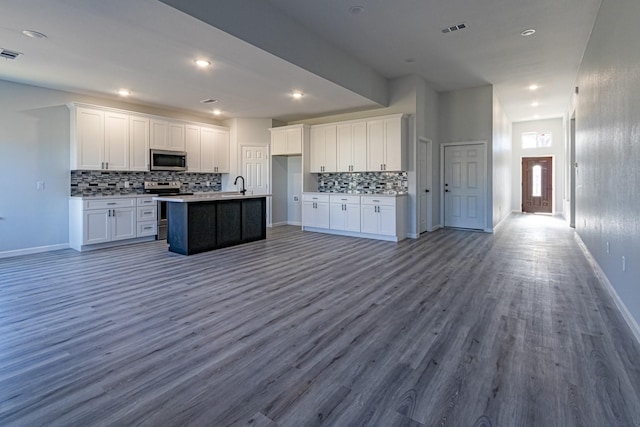 kitchen with sink, wood-type flooring, a center island with sink, appliances with stainless steel finishes, and white cabinets