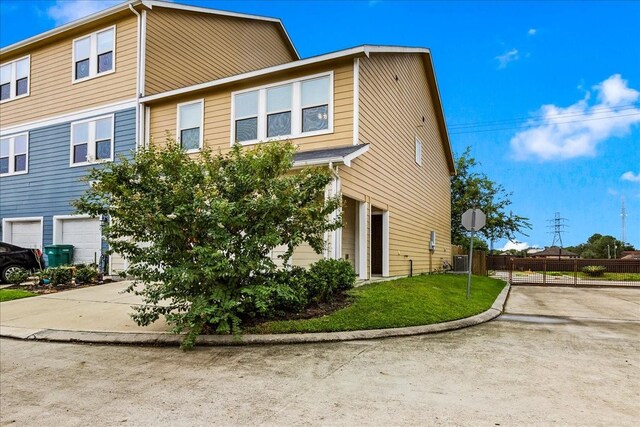 view of side of home with driveway, fence, a yard, an attached garage, and central AC unit