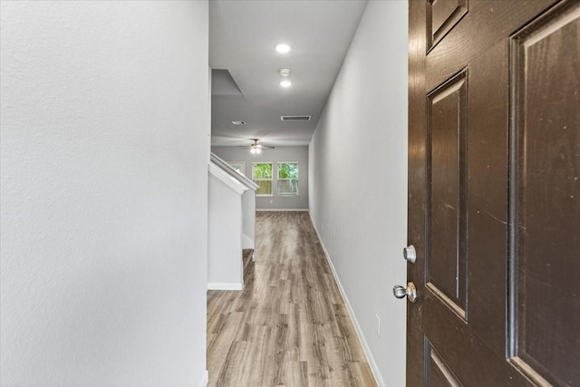 hall with stairs, light wood-style floors, visible vents, and baseboards