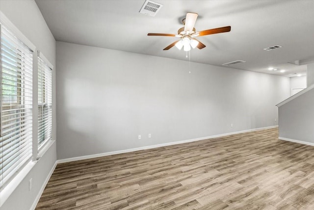 unfurnished room featuring visible vents, ceiling fan, baseboards, and wood finished floors