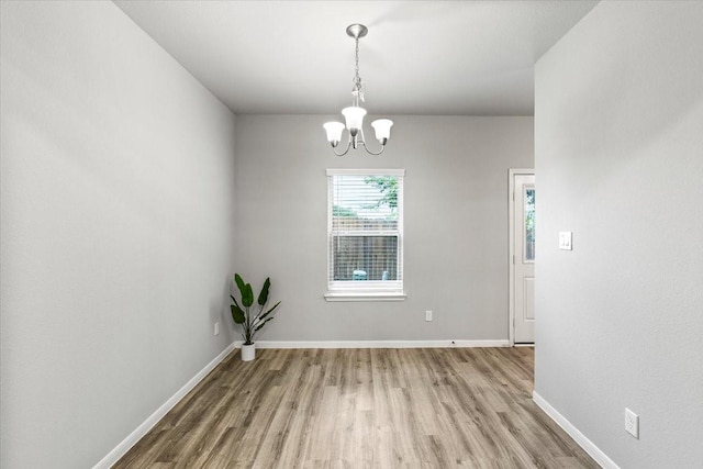 unfurnished dining area featuring baseboards, an inviting chandelier, and light wood-style flooring