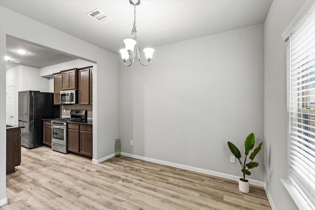 kitchen with baseboards, an inviting chandelier, stainless steel appliances, light wood-style floors, and decorative light fixtures