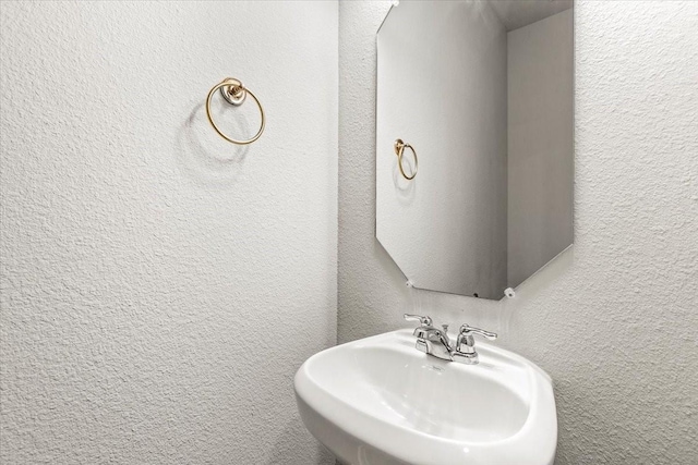 bathroom featuring a textured wall and a sink