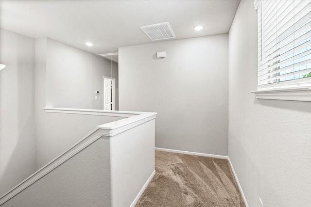 corridor with visible vents, carpet floors, baseboards, attic access, and an upstairs landing