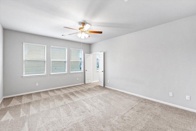 carpeted empty room with baseboards, visible vents, and ceiling fan