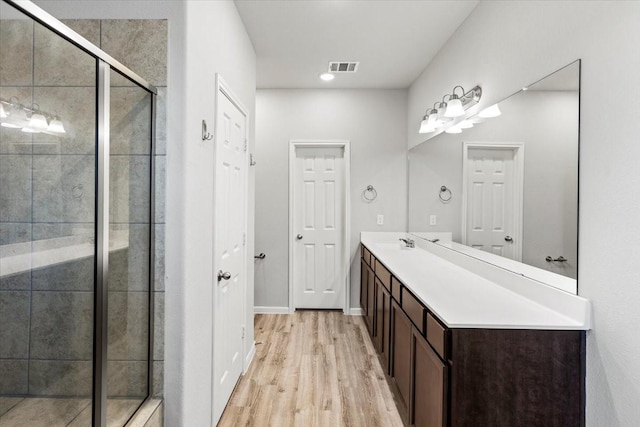 bathroom with visible vents, a shower stall, baseboards, wood finished floors, and vanity