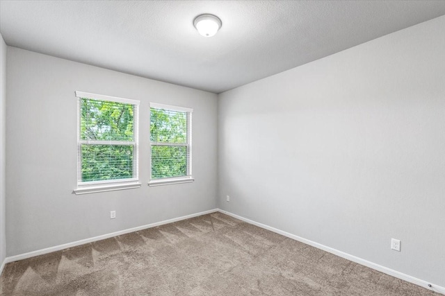 carpeted spare room featuring baseboards and a textured ceiling