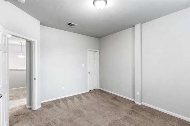 unfurnished room featuring carpet flooring, baseboards, visible vents, and a textured ceiling