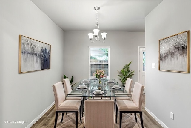 dining room featuring a notable chandelier, wood finished floors, and baseboards