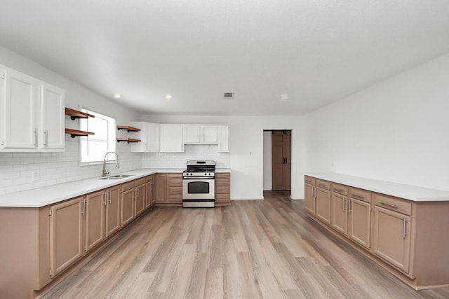 kitchen with tasteful backsplash, light hardwood / wood-style floors, stainless steel range oven, and sink