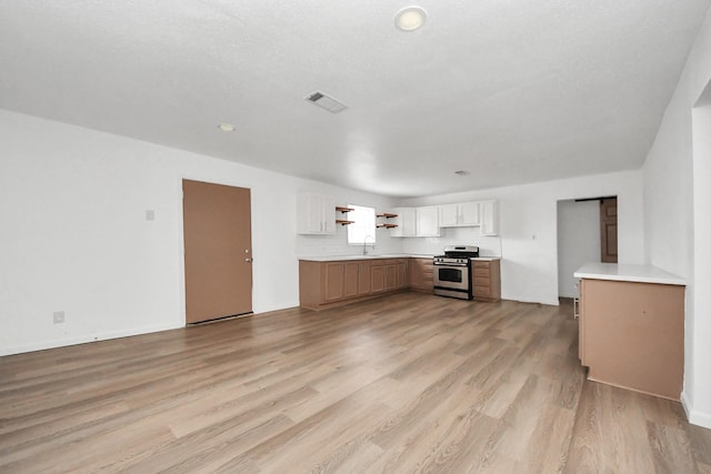 kitchen with white cabinetry, sink, light hardwood / wood-style floors, and stainless steel gas stove