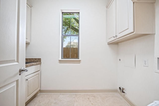 laundry area featuring light tile patterned floors, cabinet space, gas dryer hookup, electric dryer hookup, and baseboards