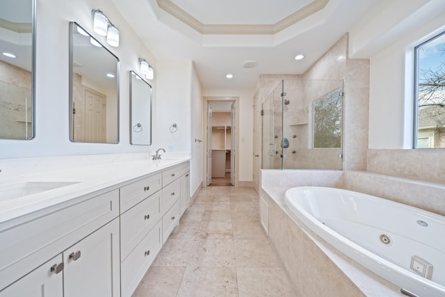 bathroom with a sink, a whirlpool tub, double vanity, a stall shower, and a raised ceiling