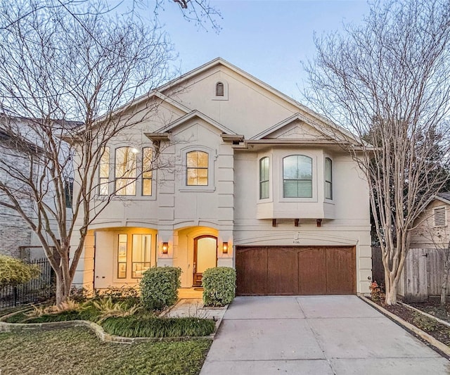 view of front of property featuring a garage, concrete driveway, fence, and stucco siding