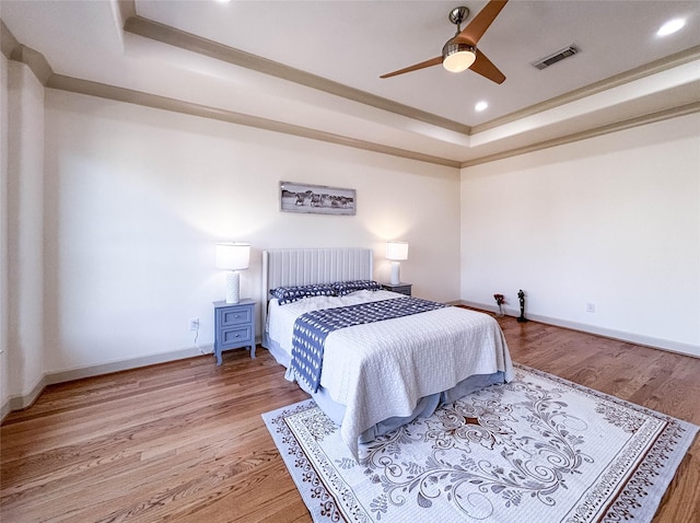 bedroom featuring baseboards, visible vents, a raised ceiling, wood finished floors, and recessed lighting