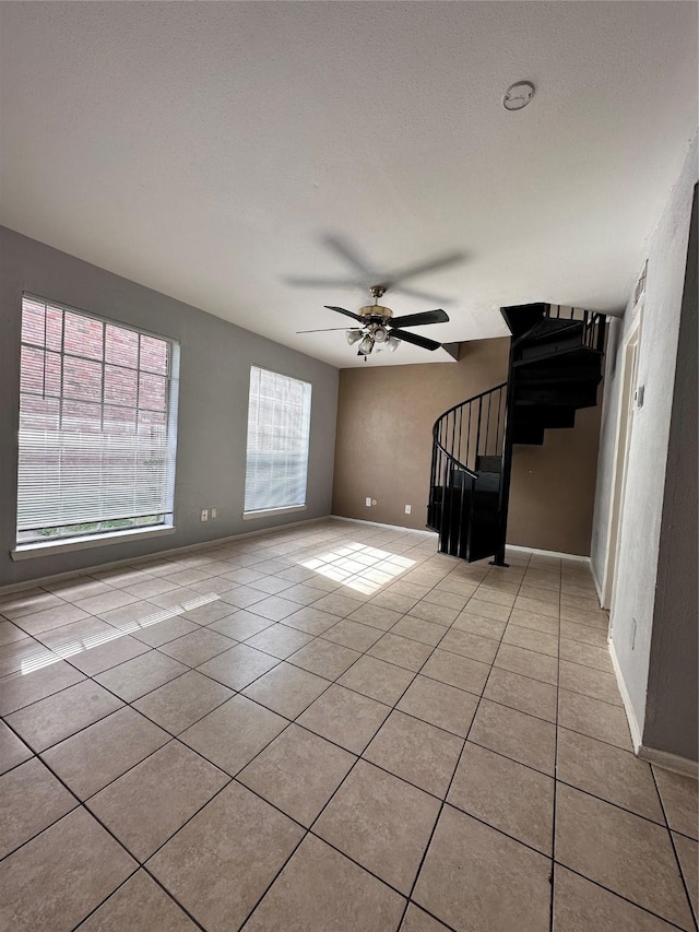 tiled spare room featuring a textured ceiling and ceiling fan