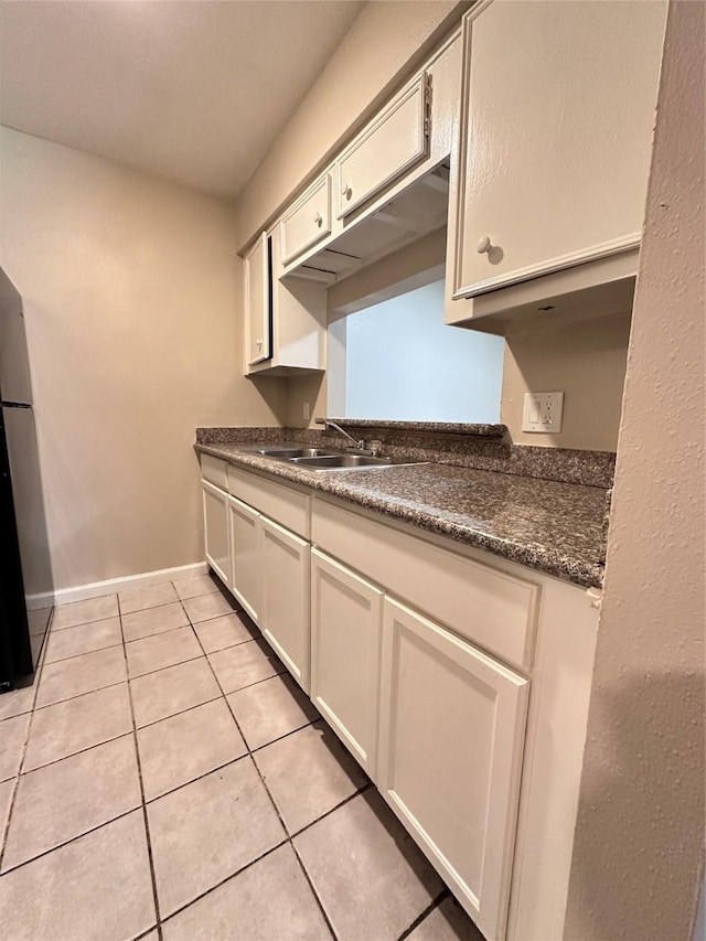 kitchen with white cabinetry, stainless steel fridge, sink, and light tile patterned floors