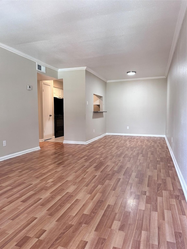 unfurnished living room with crown molding, a textured ceiling, and light wood-type flooring