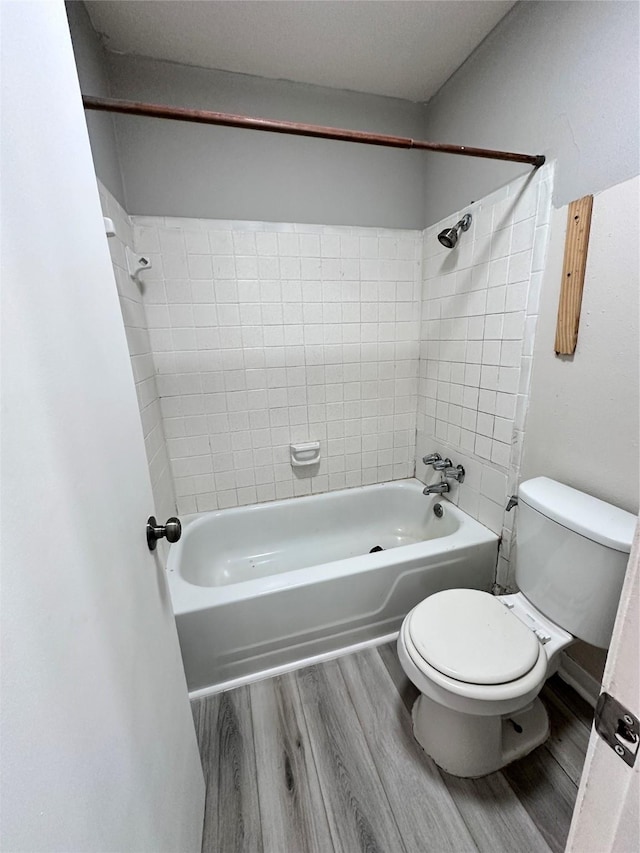 bathroom featuring hardwood / wood-style flooring, toilet, and tiled shower / bath combo