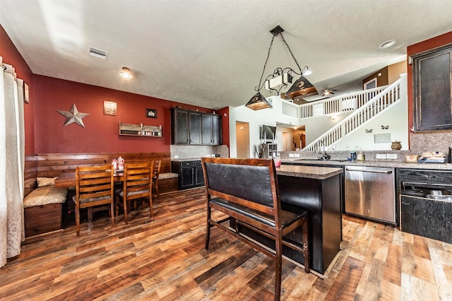 kitchen featuring hardwood / wood-style floors, pendant lighting, a kitchen breakfast bar, a center island, and stainless steel dishwasher