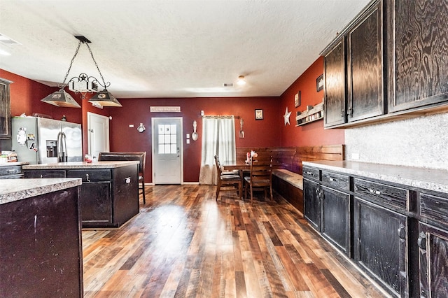 kitchen with decorative light fixtures, dark hardwood / wood-style flooring, dark brown cabinetry, stainless steel fridge with ice dispenser, and a textured ceiling