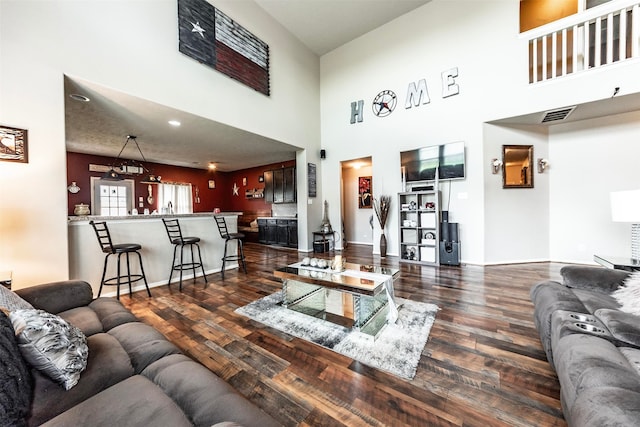 living room with a towering ceiling and dark hardwood / wood-style flooring