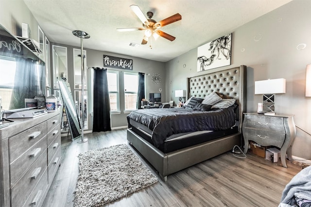 bedroom featuring ceiling fan, wood-type flooring, and a textured ceiling