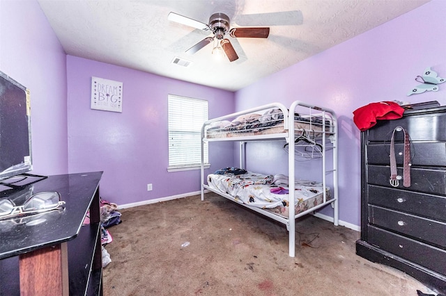 carpeted bedroom featuring ceiling fan and a textured ceiling