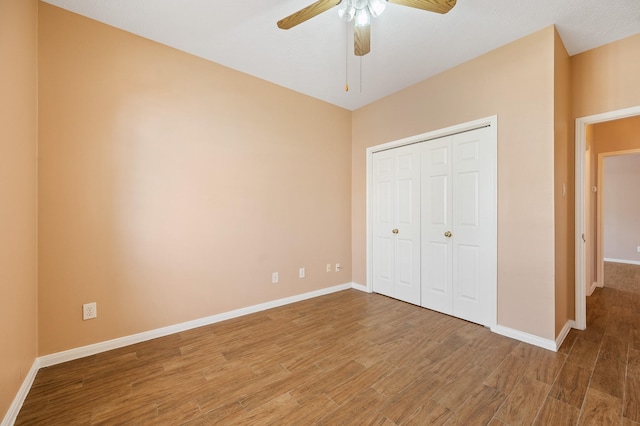 unfurnished bedroom with wood-type flooring, ceiling fan, and a closet