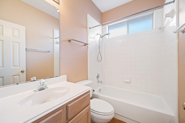 full bathroom featuring vanity, tiled shower / bath combo, and toilet